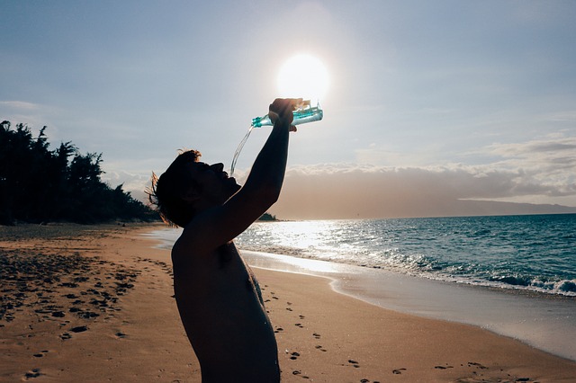man drinking water in a beach